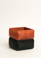 Two stacked fabric containers, one orange and one black, on a white background