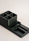 Black plastic desk organizer with compartments on a light gray background