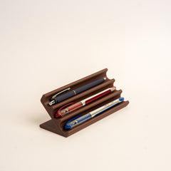 Wooden pen holder with three pens on a beige background