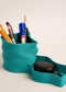 Teal pen holder with stationery items on a light background