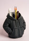 Black hoodie-shaped pen holder with stationery items on a light pink background