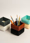 Set of colorful square-shaped pencil holders with pens on a light background in Sofa shape
