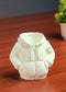 White hoodie-shaped night light on a wooden surface with a blurred plant in the background