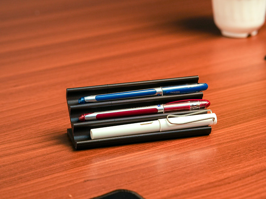 Wooden pen holder with three pens on a beige background